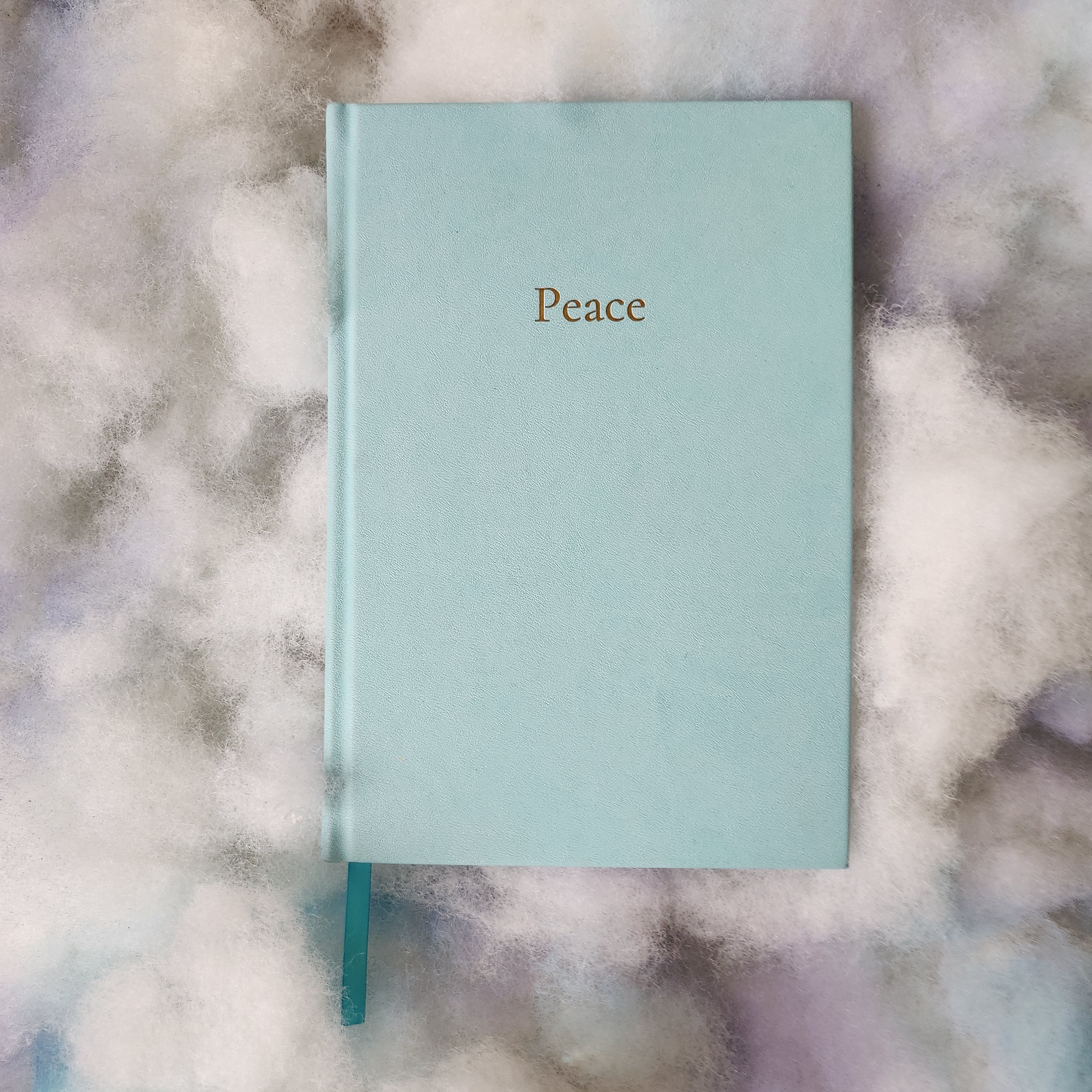 Light blue notebook with 'Peace' on a marble surface