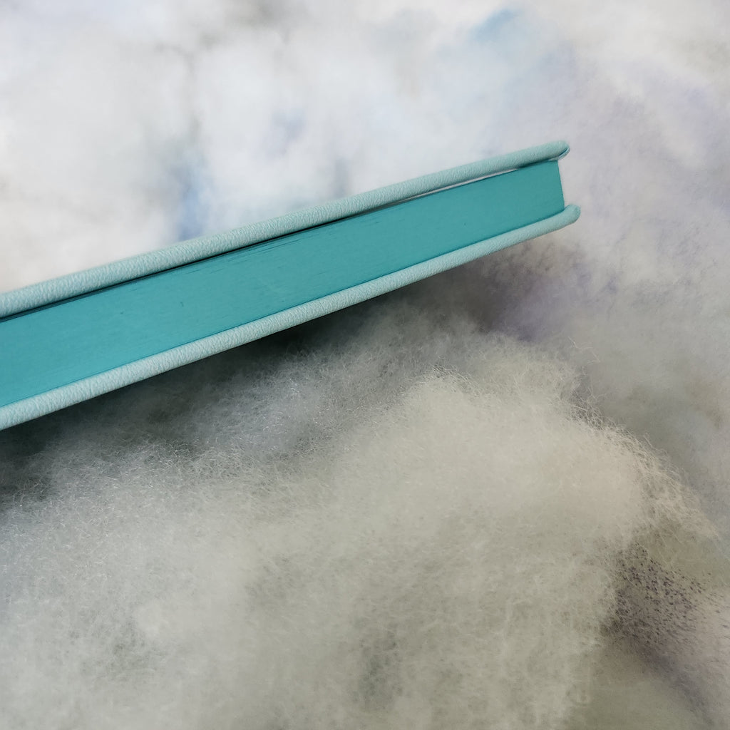 Close-up of a teal notebook on a textured surface