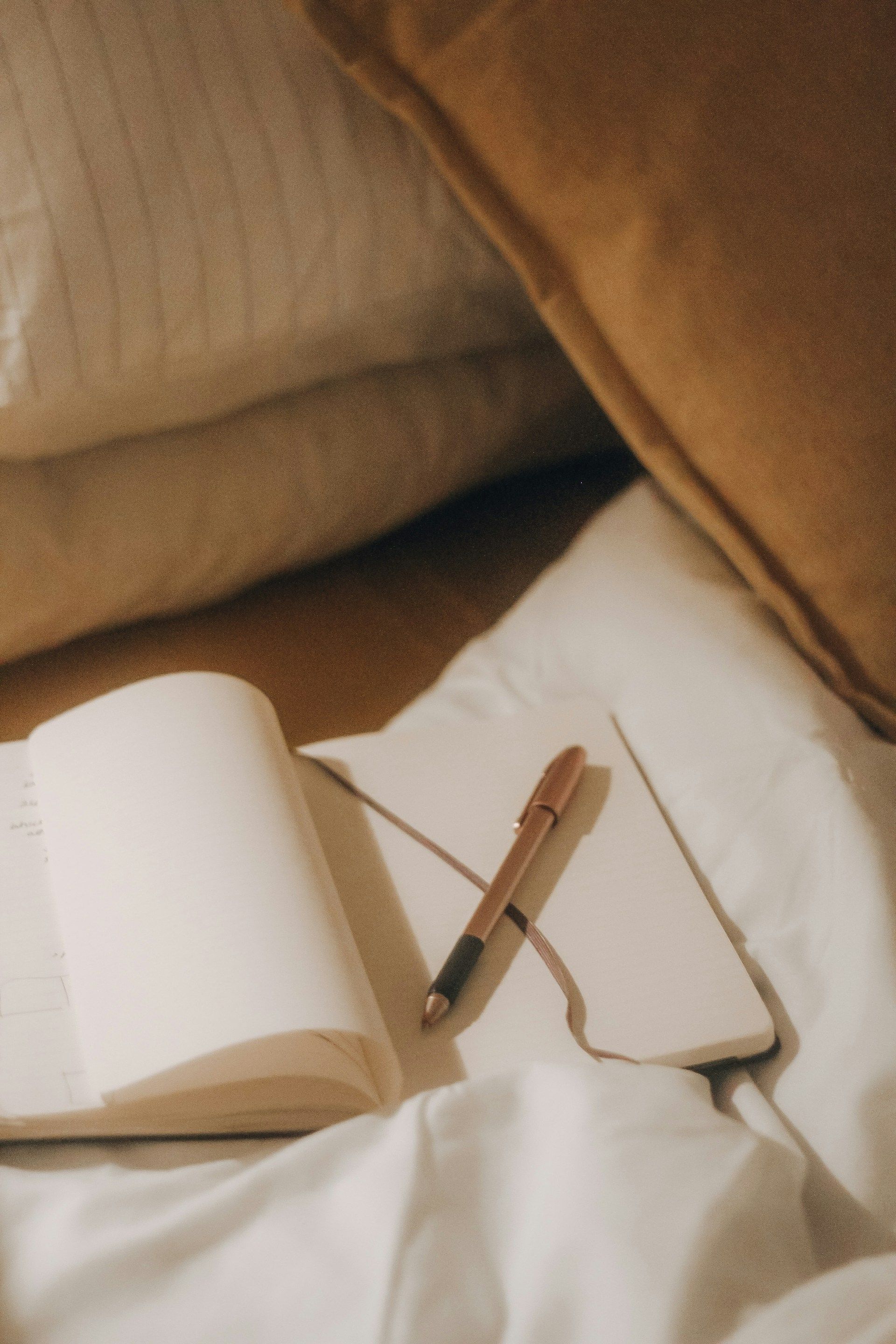 Open notebook with a pen on a bed